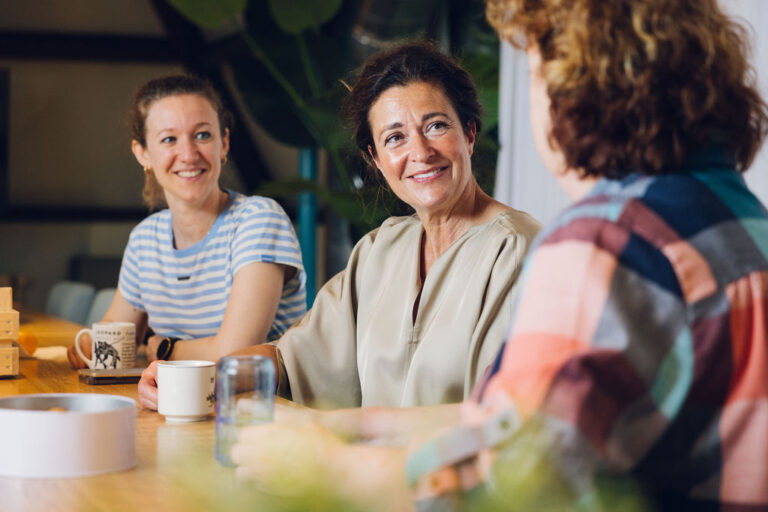 Praktijkmanager en andere collega's zitten aan tafel in de lunchruimte
