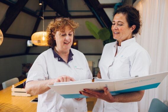 Twee Dental Clinics collega's kijken samen naar het logboek veiligheid.