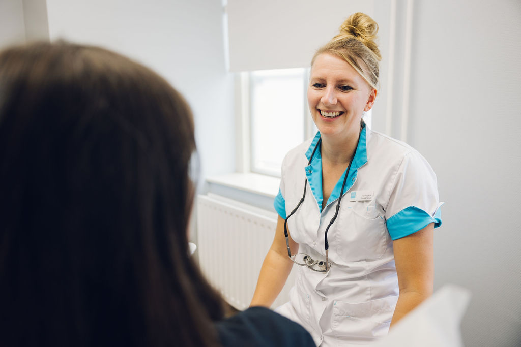 Een mondhygiënist lacht naar haar patiënt