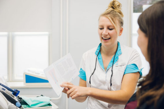 Een mondhygiënist legt iets uit aan haar patiënt aan de hand van een uitlegboekje
