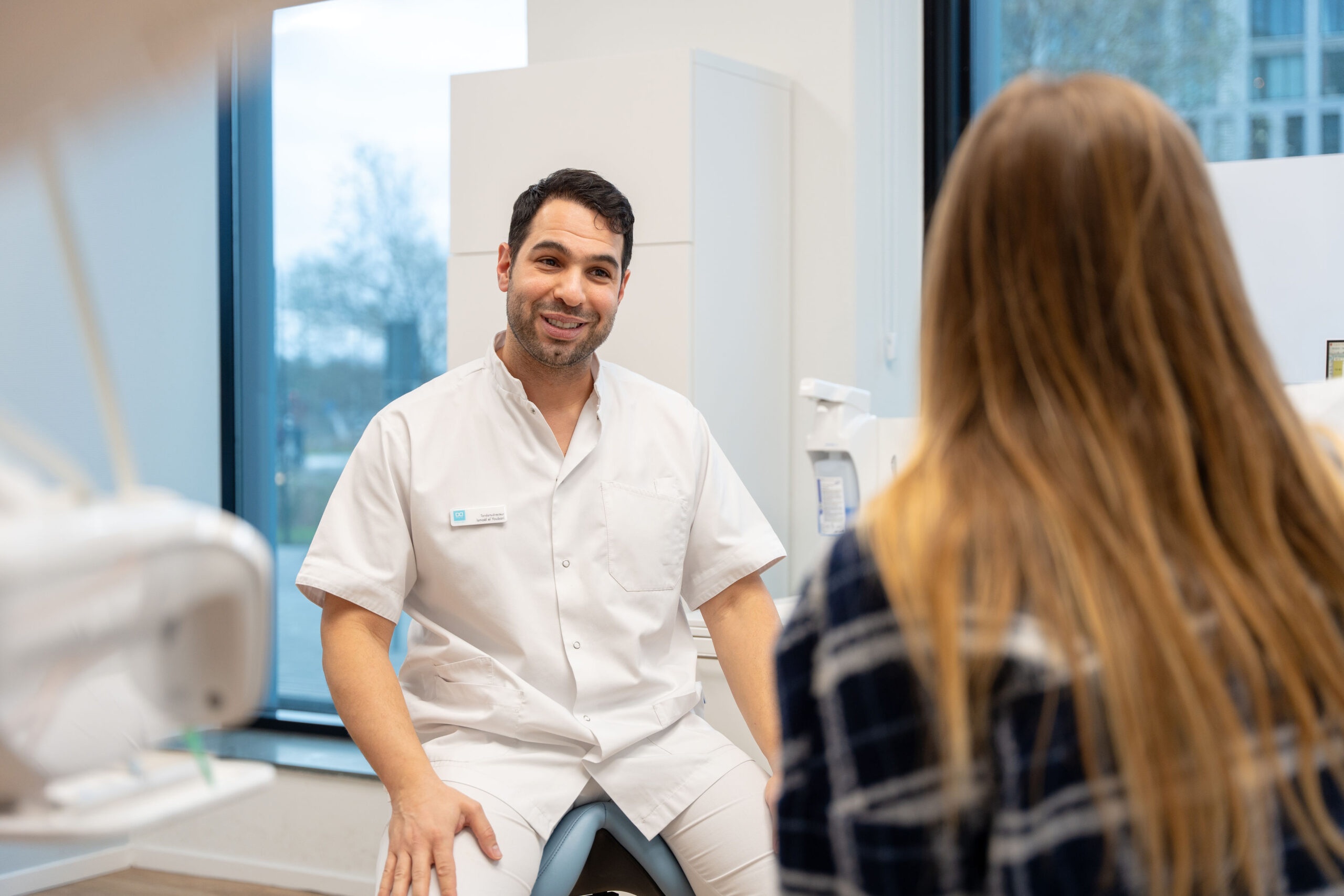 Werken bij Dental Clinics - Mannelijke tandarts in gesprek met handgebaren met een vrouwelijke patient