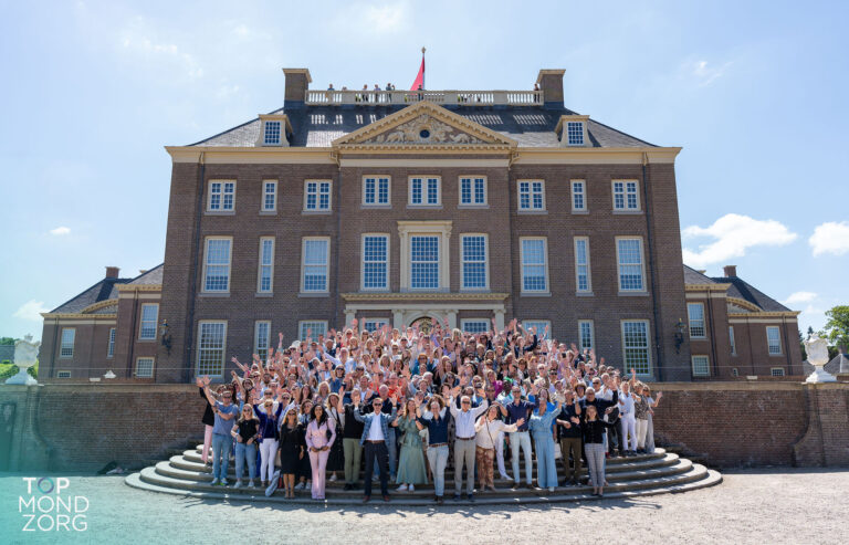 Alle aanwezigen staan op de trap van paleis het Loo en poseren juichend voor de foto
